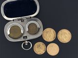 un étui argenté contenant des pièces de monnaie et un porte-clés, posé sur une surface noire