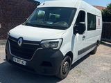 La camionnette blanche est garée sur le parking, à côté d'un mur de briques.