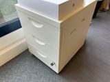 a white dresser with drawers next to a window