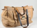 beige leather handbag with black straps on a white background