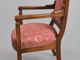 a wooden chair with a pink upholstered seat and arms