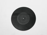 a black vinyl record on a white surface with a white background