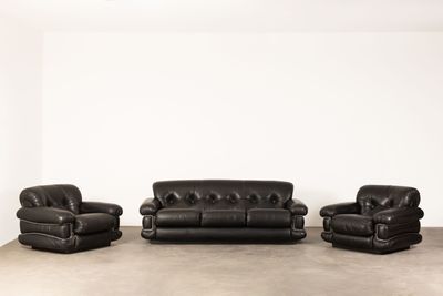 trois canapés en cuir noir et deux fauteuils dans une pièce