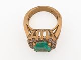 a close up of a gold ring with a green stone