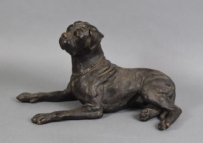 statue en bronze représentant un chien couché sur une surface grise