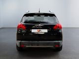 the back end of a black car in a room with a white wall
