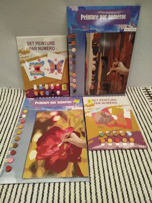 trois livres pour enfants posés sur un lit recouvert d'une couverture rayée