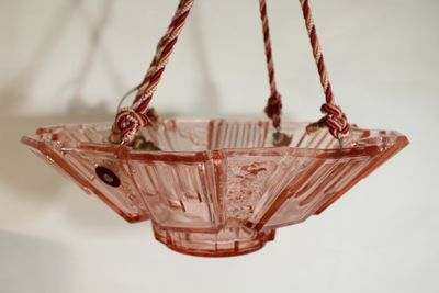a pink glass bowl hanging from a rope