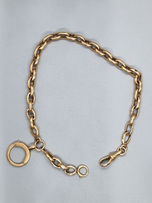 gros plan d'un bracelet en chaîne en or sur fond blanc