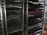many trays of food on a metal rack in a kitchen