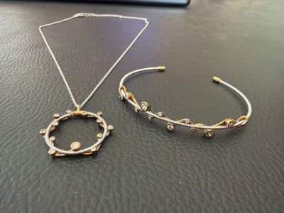 two pieces of jewelry sitting on top of a table next to each other