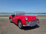 une photo d'une voiture de collection rouge garée sur le bord de la route