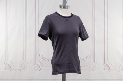 un t-shirt violet sur un mannequin posé contre un mur blanc