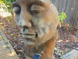 a statue of a man with his eyes closed in a garden