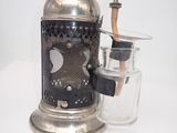a silver coffee grinder and a glass on a white table