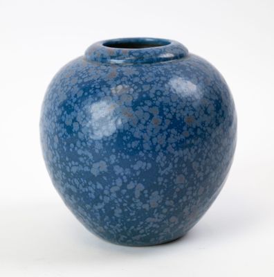 un vase bleu posé sur une surface blanche