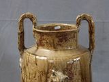 a large vase with a handle on a table