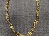 un collier à chaîne en or posé sur un tissu gris