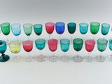 many different colored glasses lined up on a white surface