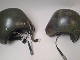 pair of military helmets with wires attached to them sitting on a table
