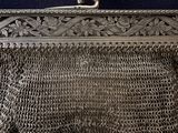 a silver purse with two birds on top of it