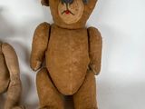 two teddy bears sitting next to each other on a white surface