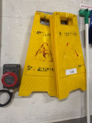 un panneau d'avertissement jaune accroché au mur à côté d'un poteau vert