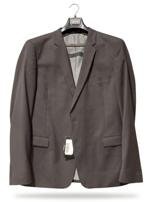 a gray jacket hanging on a hanger on a white wall