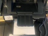 une imprimante posée sur un bureau, à côté d'un téléphone