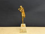 a gold statue of a woman holding a bird on a marble base