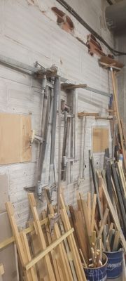 Plusieurs morceaux de bois sont empilés contre un mur dans un atelier.