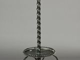 wrought iron candle stand with a glass candle holder on top of it
