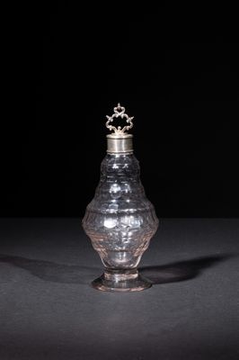 an old silver vase with a crown on top on a black surface