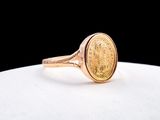 un gros plan d'une bague en forme de pièce d'or posée sur une surface blanche