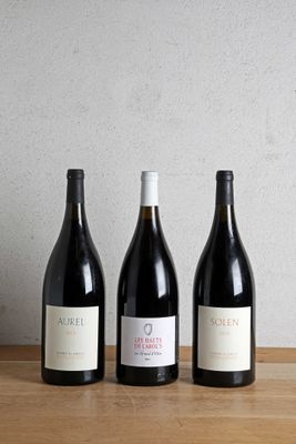 three bottles of wine are lined up on a wooden table
