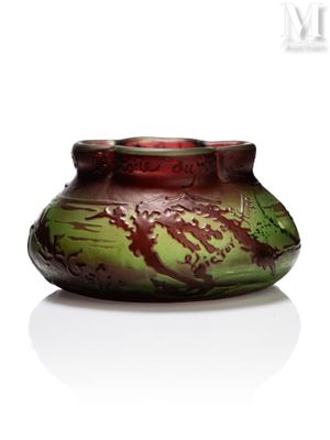 un vase vert et rouge posé sur une surface blanche