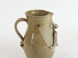 a small vase with a handle on a white surface