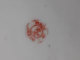 a close up of a white plate with a red design on it