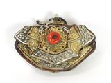 silver and gold broochle with a red flower on top of it