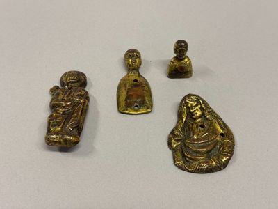 three small brass figurines are sitting on a white surface