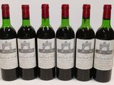 six bottles of red wine are lined up on a table