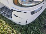a white truck that has been damaged and is parked in the grass