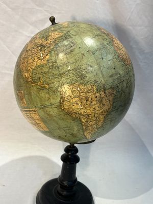 un globe vert posé sur un socle noir, sur fond blanc