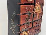 a black and red chest of drawers with a vase on top of it