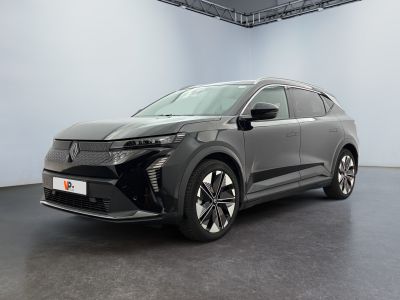 Une voiture grise est garée dans une grande pièce au sol noir.