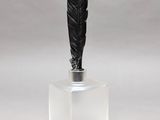 a black feather on top of a clear glass container