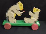 a wooden toy of a bear and a bear sitting on a skateboard