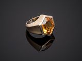 a gold ring with a faceted citrine stone on a black surface