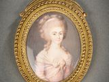 un portrait ancien représentant une femme en robe blanche, dans un cadre doré