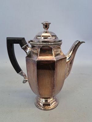 une théière ancienne en argent, dotée d'une anse noire, posée sur une table